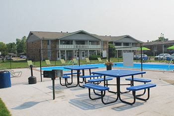 a picnic table in front of a pool with a building in the background